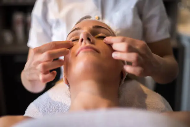 Close up unrecognizable beautician massaging women face