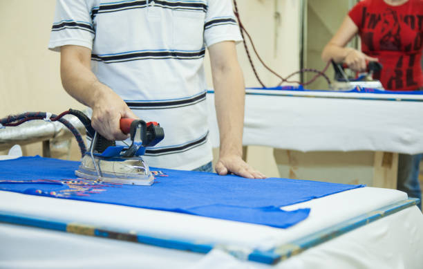 werknemer met behulp van een ijzer in textielfabriek - uitbeenhandschoen stockfoto's en -beelden