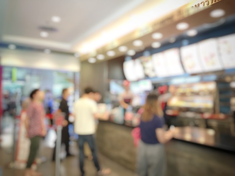 blurred abstract image of people standing for wait to order some food and make payment in fast food restaurant. Use as background image. vintage tone color and light effect.