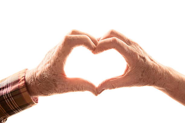 Senior couple forming heart with hands stock photo