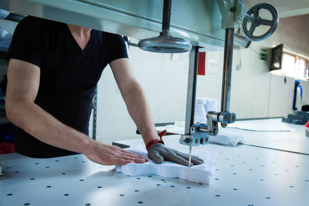 werknemer met behulp van een machine in de fabriek met ijzeren handschoen - uitbeenhandschoen stockfoto's en -beelden