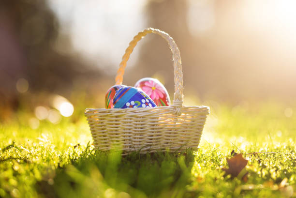 Easter basket with traditional painted eggs in the garden or grass.