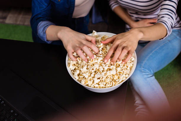 istock Female hands take popcorn from a white big plate 951876110