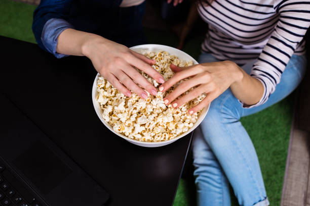 istock Female hands take popcorn from a white big plate 951876114