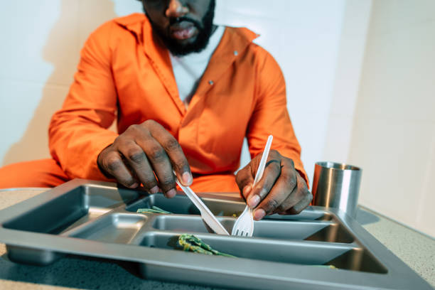 cropped image of african american prisoner eating in prison cell cropped image of african american prisoner eating in prison cell prison meal stock pictures, royalty-free photos & images