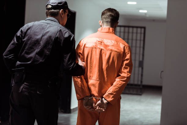 rear view of prison officer leading prisoner in handcuffs in corridor rear view of prison officer leading prisoner in handcuffs in corridor prison guard stock pictures, royalty-free photos & images