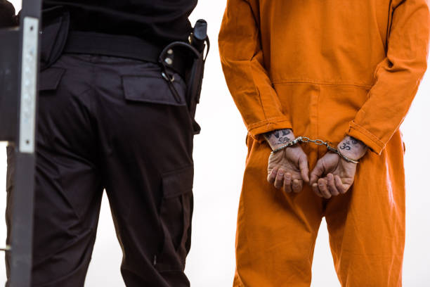 istock cropped image of prison guard leading criminal in handcuffs 951884844