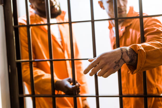 istock multicultural prisoners standing near prison bars in prison cell 951890922