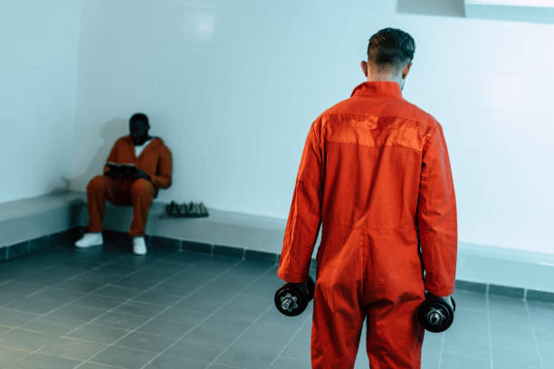 istock rear view of prisoner training with dumbbells in prison cell 951894398