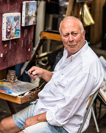 Paris, France - July 06, 2017: The painter works at the open air artist market at the Tertre Square (Place du Tertre) in the Montmartre district.