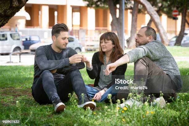 Foto de Três Amigos Sentado Na Grama No Parque Público Fumar e mais fotos de stock de Maconha