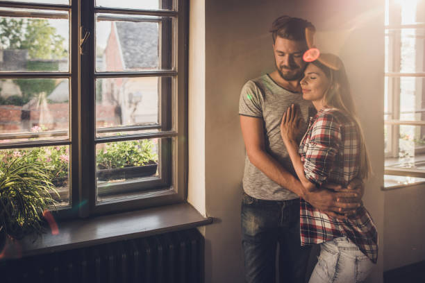 istock Young affectionate couple standing embraced with their eyes closed by the window. 951914136