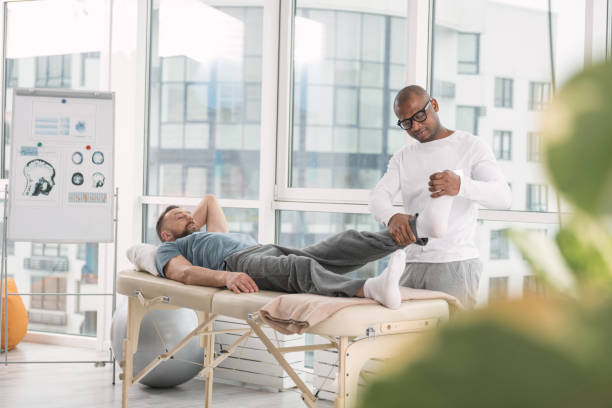 istock Smart nice doctor looking at his patients feet 951923090