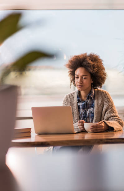 istock African American woman reading an e-mail during breakfast time at home. 951923252