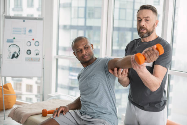 Nice pleasant man looking at his hand My strength. Nice pleasant man looking at his hand while lifting dumbbells sports physical stock pictures, royalty-free photos & images