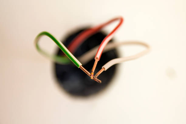 Several exposed electrical copper wires protruding from a whitewall.