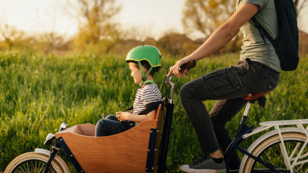 Woohoo! Father and son riding a cargo bike in nature cargo bike photos stock pictures, royalty-free photos & images