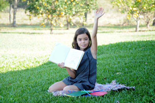 girl sitting on chair in front of grassy meadow with books
