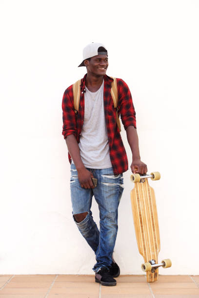 istock Full length smiling young guy standing against wall with skateboard 951961214
