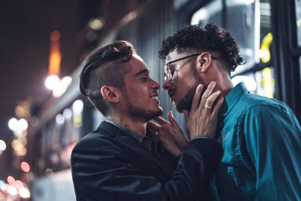 chicos gay besándose después del trabajo en la noche - gay man homosexual men kissing fotografías e imágenes de stock