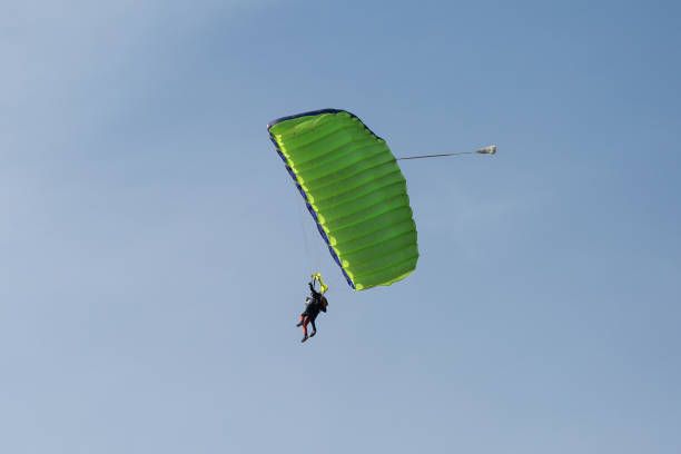 istock Parachutists: Instructor and Beginner with Green Parachute against Clear Blue Sky 951969714