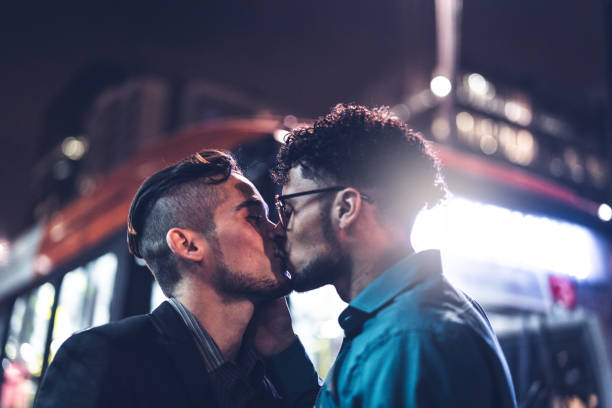 chicos gay besándose después del trabajo en la noche - gay man homosexual men kissing fotografías e imágenes de stock