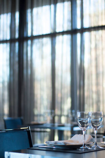 Restaurant cafe bar in luxury hotel with place settings for breakfast, lunch and dinner with wine water glasses and plates.