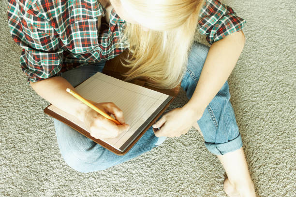 istock The woman sits on the carpet and writes 951979762