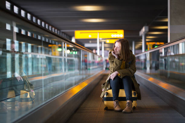 girl with the luggage at the airport the girl is riding on the travolator at the airport with a large yellow suitcase "n airport travelator stock pictures, royalty-free photos & images