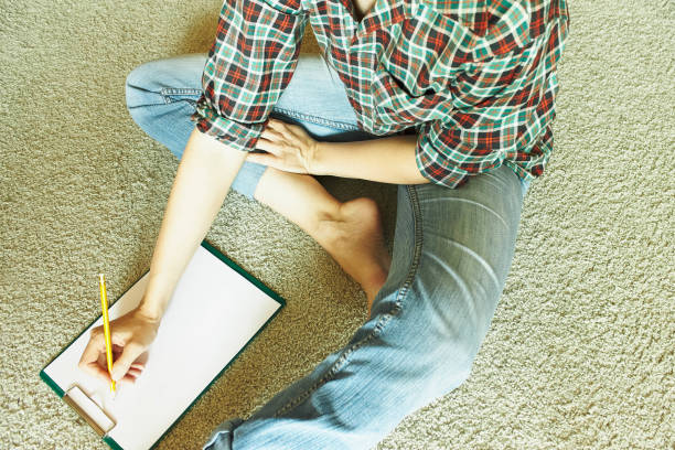 istock The woman sits on the carpet and writes 951979886