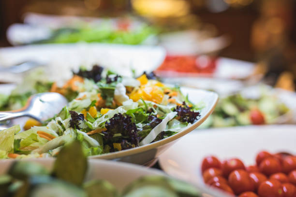 A fresh buffet of healthy salads A fresh buffet of a colorful variety of healthy organic salads. Focus is on a salad bowl of mixed leafs and carrots, and there is a bowl of tomatoes on the right side. buffet stock pictures, royalty-free photos & images