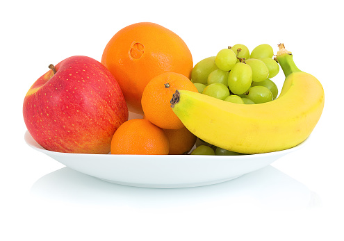 Bowl of fresh fruits isolated on white background with shadow reflection. Apple orange mandarin grape and banana in white bowl.