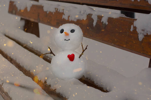 snowman sits on a bench in a snowy park