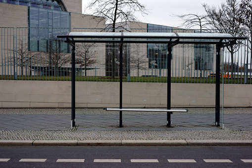 The new built glass shelter of a modern bus stop at a street.