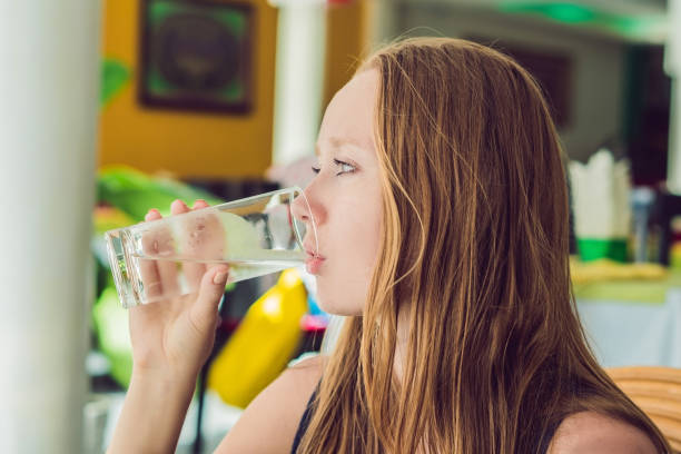 istock Young woman drinks water in a cafe 951997044