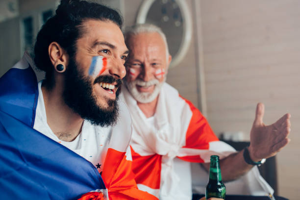 istock Happy friends supporting different national teams on a world soccer championship watching game together from home 952000430