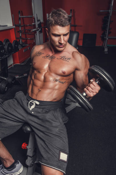 a man doing biceps workout. - muscular build men tattoo human arm imagens e fotografias de stock