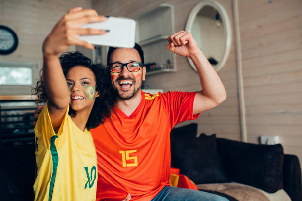 istock Couple watching soccer game on TV and making selfie 952002164