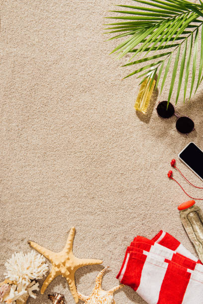istock top view of striped towel with various objects lying on sandy beach 952011198