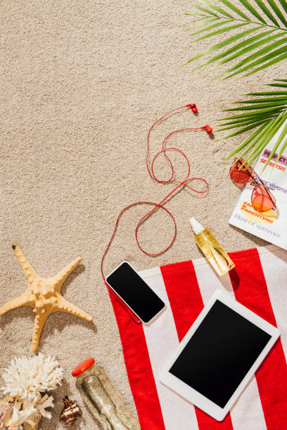 istock top view of gadgets on striped towel on sandy beach 952011244