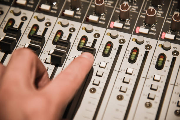 istock close-up hands of sound engineer adjusting audio mixer controller for live music and studio equipment. This is a quality audio system for professionals. vintage tone & effect light in control room. 952011794