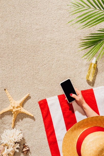 istock cropped shot of woman in hat using smartphone while relaxing on sandy beach 952012310