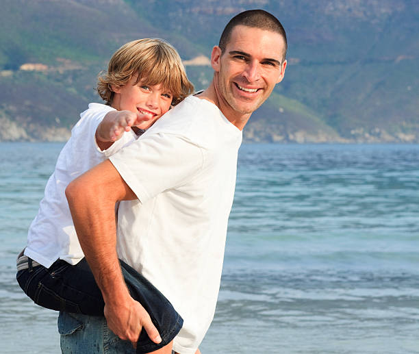 istock Father giving his son piggyback ride on the beach 95201271