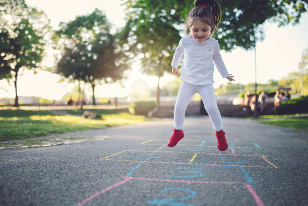 Jumping child playing hopscotch Cute and gorgeous child playing in the park jumping on a hopscotch. drawing of spring free stock pictures, royalty-free photos & images