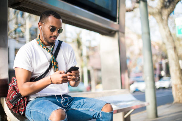 istock Handsome man using mobile phone at the bus station. 952016024