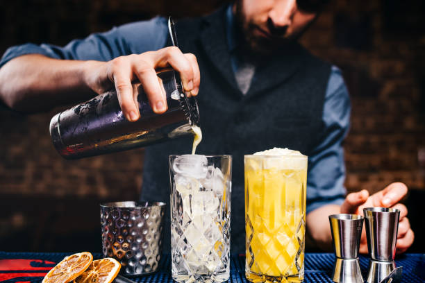 istock Elegant bartender pouring fresh orange vodka cocktail over ice in crystal glassware 952019508