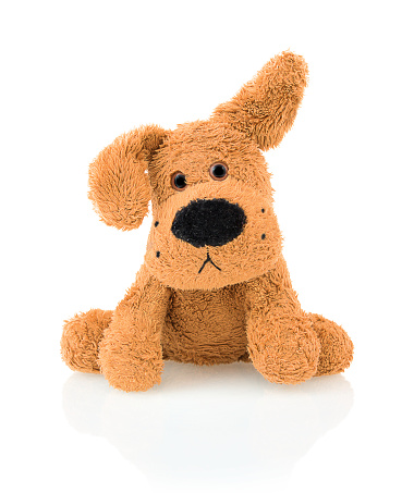 Cute dog doll isolated on white background with shadow reflection. Playful adorable bright brown dog sitting on white underlay.