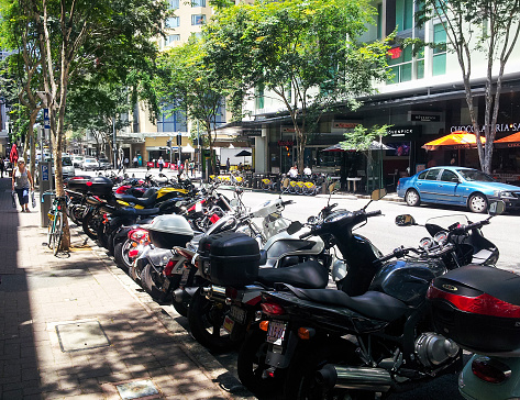 Urban street with motorcycles parked along one side and for rent bicycles and cars on the other in Brisbane Queensland Australia Nov 21 2013