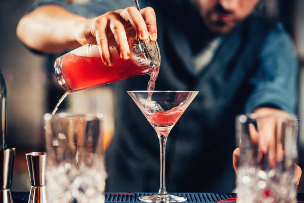 bouchent les détails du barman versant vodka cosmopolite cocktail dans un verre à martini - shaker photos et images de collection