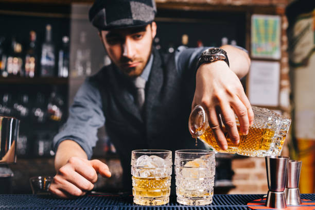 istock Barman pouring whiskey cocktail in crystal glasses 952022710